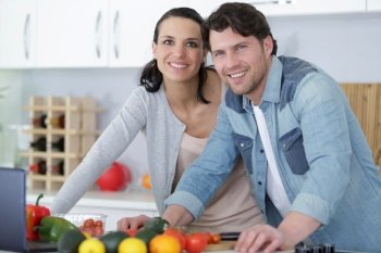 portrait of a cheerful young couple cooking salad together