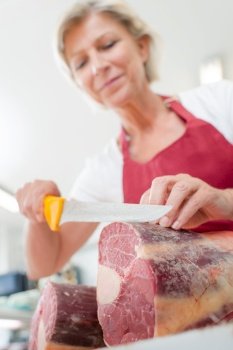 Female butcher slicing some beef