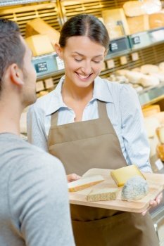 Shop assistant showing customer a tray of cheeses