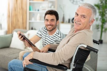 man holding tablet for man in wheelchair