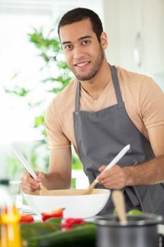 handsome man cooking at home preparing salad in kitchen