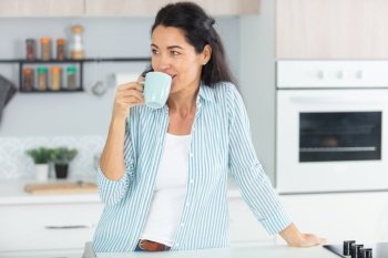 young happy woman drinking coffee on the kitchen