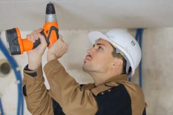 a construction builder drilling ceiling