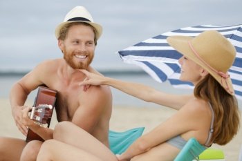 young caucasian couple with guitar on beach