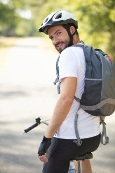 rear shot of biker with cycling clothing helmet and backpack