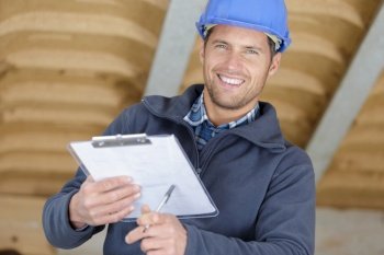 man builder smiles and stands with clipboard indoors