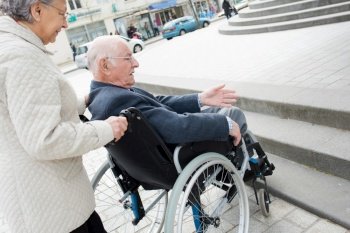 senior couple having trouble moving disabled husband through the city