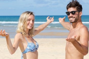 couple showing deserted beach with open arms