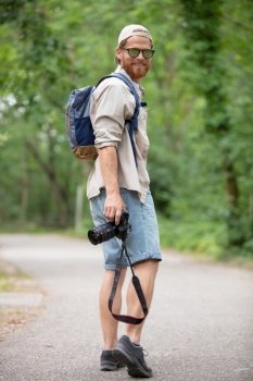 man walking in the countryside carrying a camera