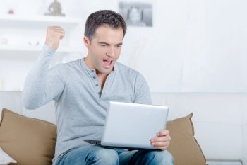 Man looking at laptop, making gesture of success