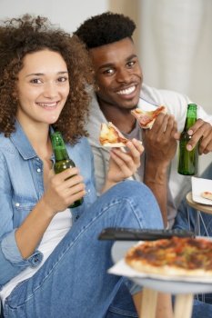 hipster couple holding slices of pizza and bottles of beer