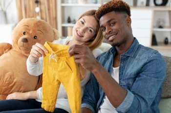 young future parents with chlidrens clothes at home