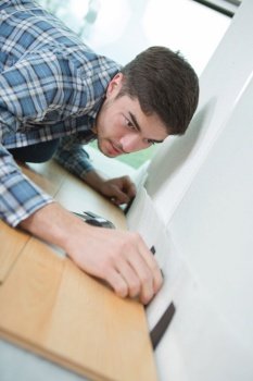 young man butting laminate flooring up against wall
