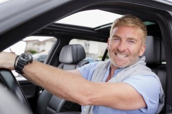 happy man smiling seated in his car holding the key