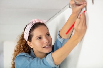 indoor shot of young woman using leveling tool at home