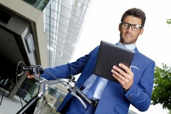 stylish businessman with bicycle using digital tablet outdoors