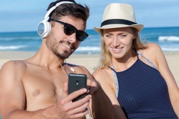 couple listening to mp3 player on the beach