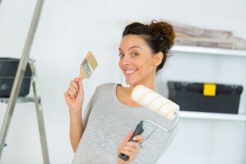 portrait of woman holding paintbrush and roller