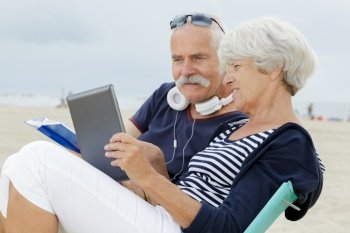 back view of a senior couple sit on beach