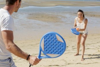 a happy couple playing beach tennis
