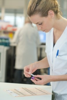 Laboratory worker sticking label onto blood sample