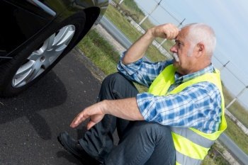 discouraged retired man unable to change car tyre