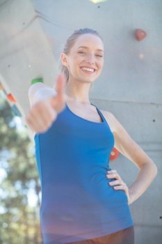 woman by climbing wall making thumbs-up gesture
