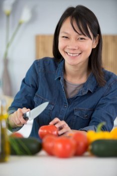 young asian lady chopping a tomato