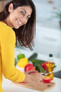 beautiful woman preparing tasty vegetable salad in kitchen at home