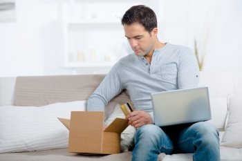 man unpacking online purchase at home