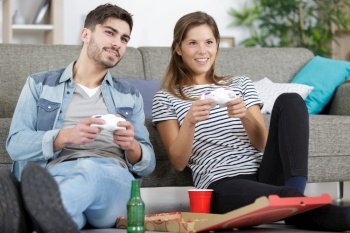 couple on couch playing video game and having a beer
