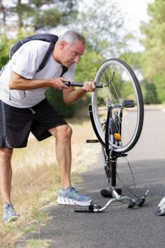 man pumping bicycle wheel with air pump