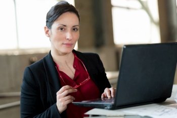 female boss wearing stylish elegant white suit holding laptop