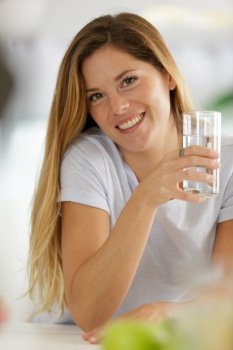 beautiful young woman smiling while holding a glass of water