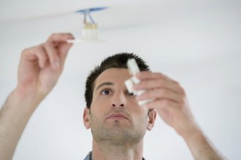 Man fitting light to ceiling