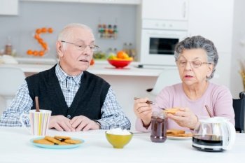 elderly husband and wife having breakfast and talking at table