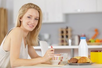 beautiful young blonde woman eating cereals in the morning
