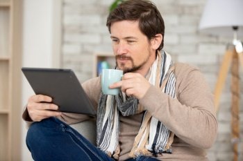 smiling man working with tablet and coffee cup at home