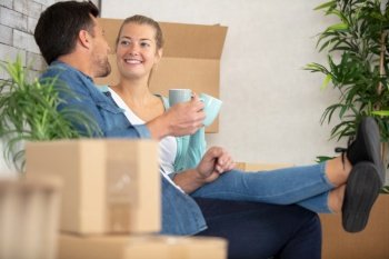 couple relaxing with a coffee surrounded by cardboard boxes