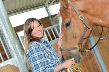 Woman feeding hay to a horse