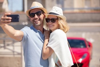 beautiful young couple taking selfie near car