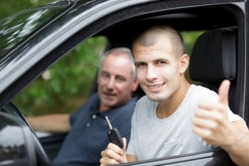 smiling man at camera showing thumbs up in his car