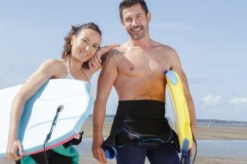 a middle aged couple holding bodyboards