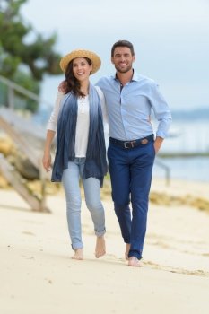 couple on casual attire walking on the beach