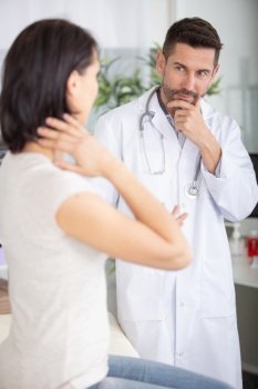 mature caucasian male doctor examining and consulting young beautiful woman