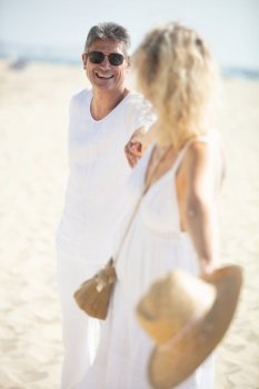 carefree mature couple holding hands on the beach