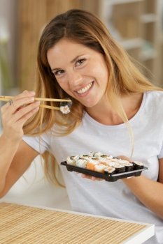 beautiful young woman with sushi roll at home