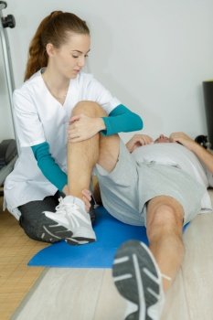 female nurse assisting senior man in leg exercise