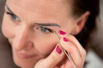 woman plucking her eyebrows with tweezer