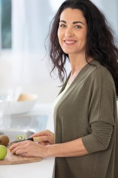 mature woman slicing fruits at home
